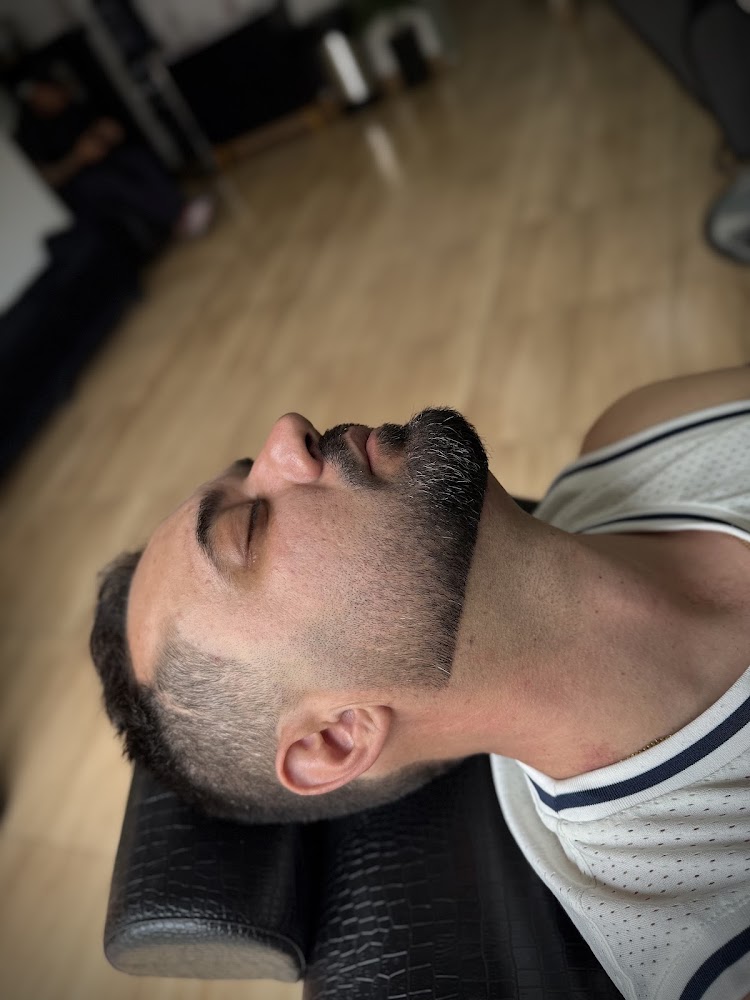Cliente reclinado na cadeira com barba e cabelo recém-alinhados
